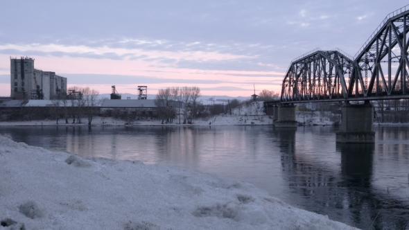 of Railway Bridge Over the River at Dawn with a Mountain Forest and Traffic Highway in the