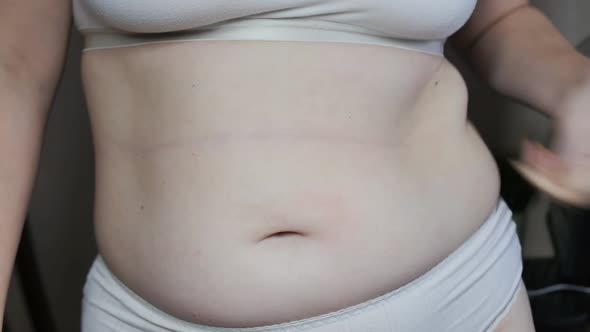 a Woman Shows Excess Weight on Her Stomach and Sides and is Nervous