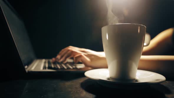 Typing on a laptop keyboard, drinking coffee