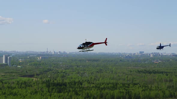 A Bluewhitered Bell Helicopter Flies Against a Background of Blue Sky and Green Fields Followed By