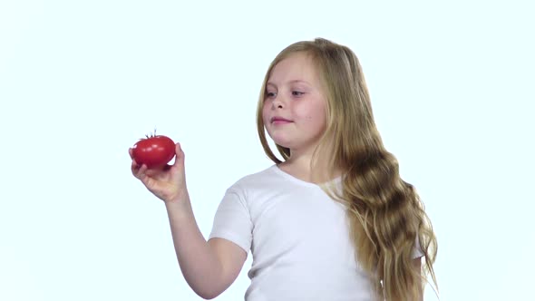 Baby Looks at a Tomato, Admires It and Shows a Thumbs Up, White Background, Slow Motion alt