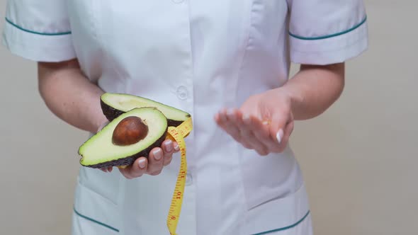 Nutritionist Doctor Healthy Lifestyle Concept - Holding Organic Avocado Fruit and Measuring Tape alt