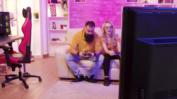 Excited Young Couple Sitting on Sofa and Playing Video Games alt