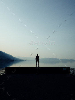 Man silhouetted against a beautiful alpine lake