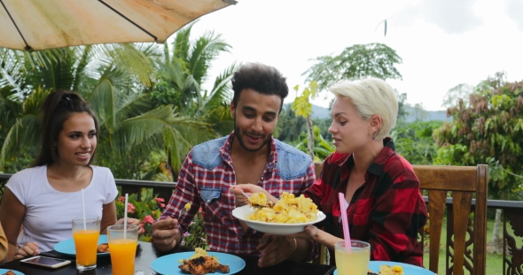 People Talking Passing Food Eating On Terrace Young Friends Sitting At Table Outdoors Laughing