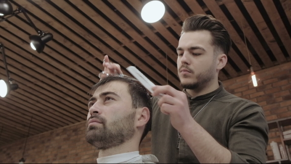Master Cuts Hair and Beard of Men in the Barbershop, Hairdresser Makes Hairstyle for a Young Man alt