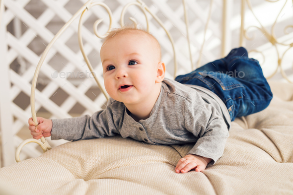 Adorable baby boy in sunny bedroom. Newborn child - Stock Photo - Images