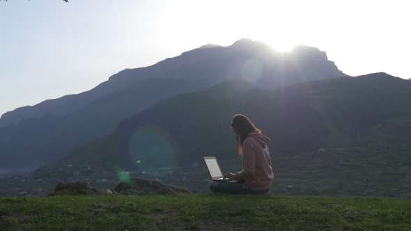 Woman with Laptop on the Background of a Mountain