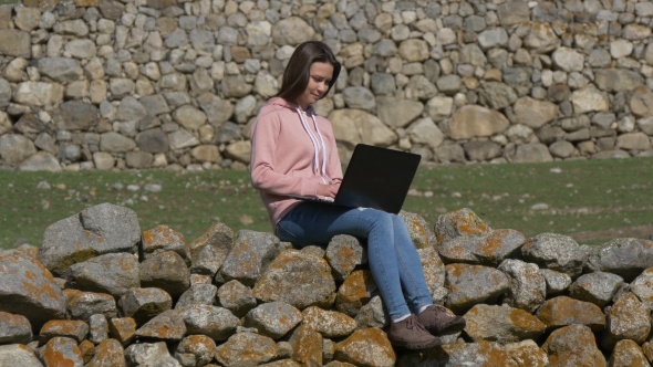 Woman with Laptop on a Stone Wall