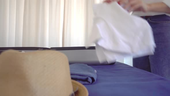 A young beautiful woman in a Santa Claus hat collects things in a suitcase alt