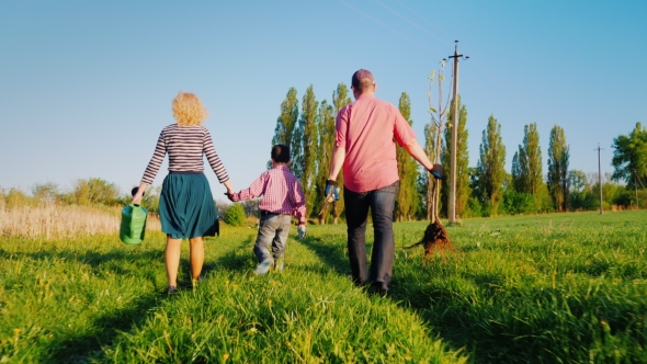 A Family of Farmers with a Small Son Go Together To Plant a Tree alt