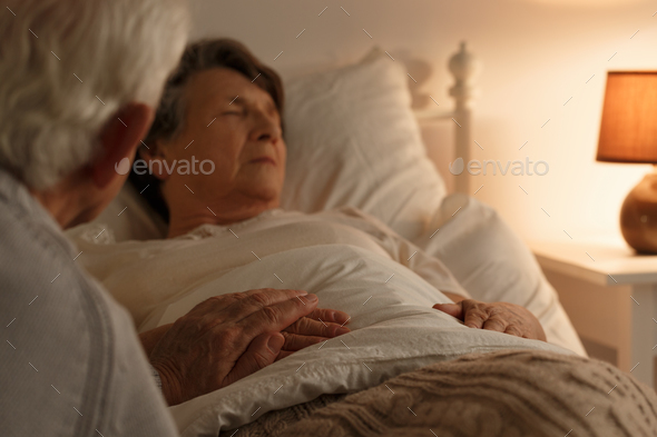 Husband holding dying wife's hand - Stock Photo - Images