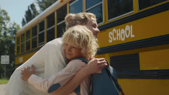 Smiling Mom Hugging Son Near School Bus alt