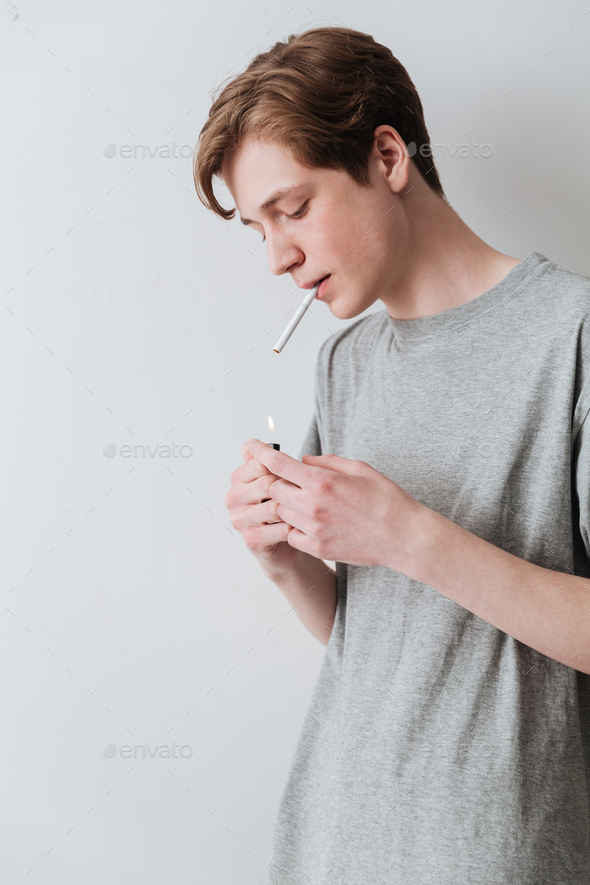 Vertical image of young man smoking cigarette Stock Photo by vadymvdrobot