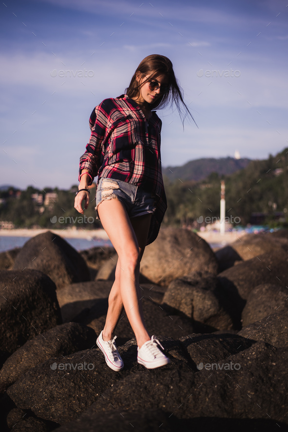 Mevrouw Verslaving bouwen Sexy Girl in flannel shirt on the rocky beach. Stock Photo by romankosolapov