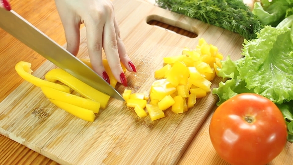 Female Hands Cutting Yellow Bell Pepper on the Wooden Cutting Board