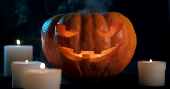 Halloween Pumpkin Surrounded by Candles and Bluish Smoke on Dark Background