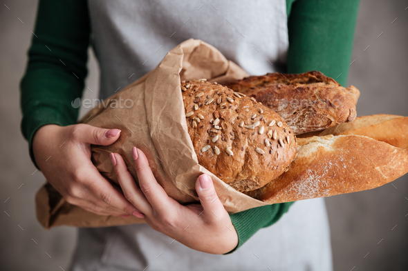 Close up photo of female baker holding bag with bread - Stock Photo - Images
