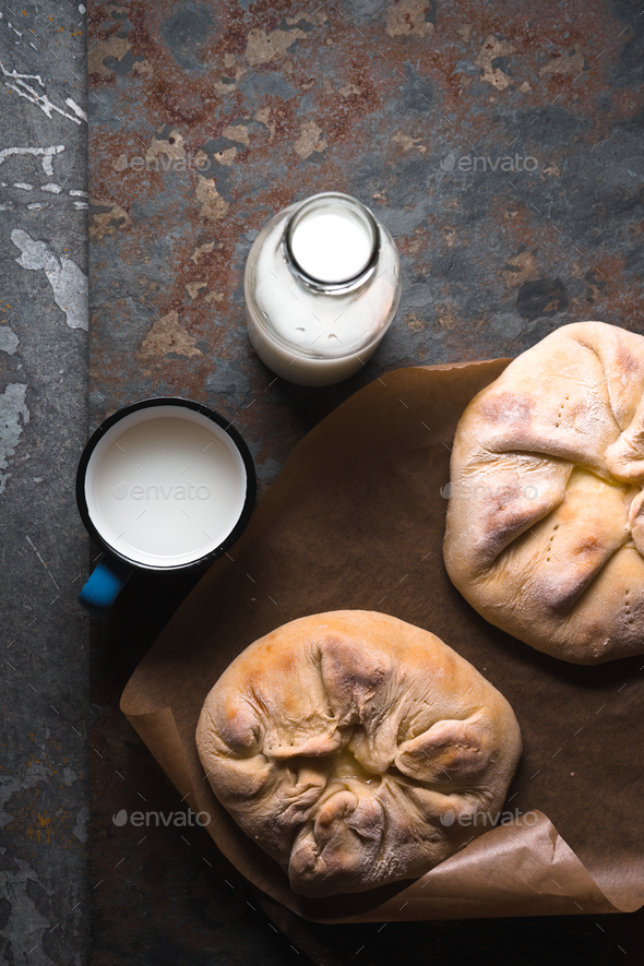Ready-made khachapuri with cheese on parchment and milk in a bottle diagonal