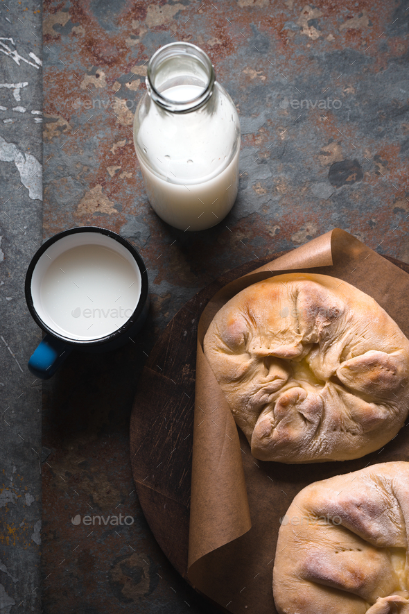 Ready-made khachapuri with cheese on parchment and milk in a bottle