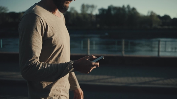 Young Bearded Man Walking with Phone in Hand alt
