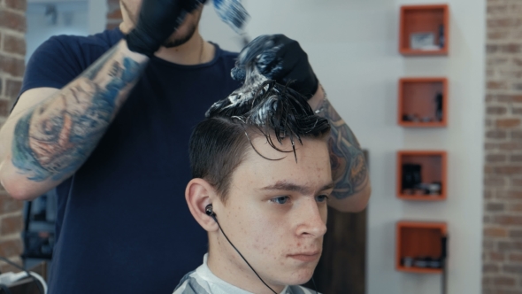 Handsome Man Gets a Haircut in the Salon . Toning Hair in Blue. alt