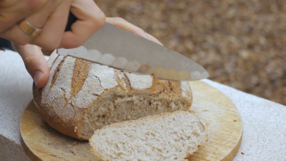 Men's Hands Cut a Loaf of Bread alt