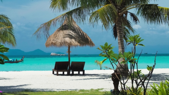 Beach Chairs, Umbrella and Palms on the Beach. Longtail Local Boat Passing By. Koh Lipe Island alt