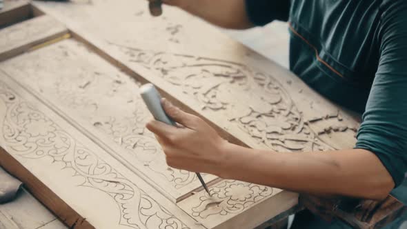 Man engraving decorations on a  wooden plank