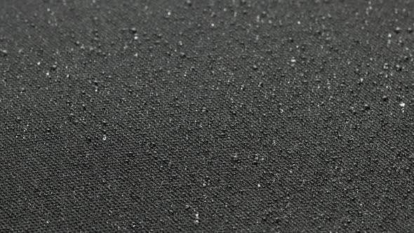Spinning Closeup Background of Black Hydrophobic Fabric Covered with Water Drops