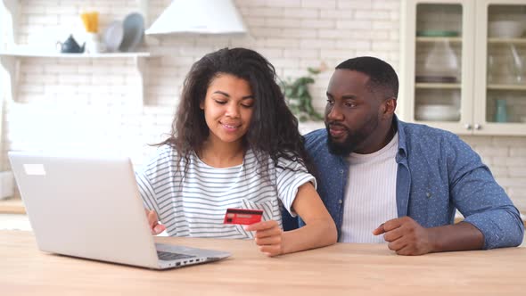 Cheerful AfricanAmerican Couple with Laptop Shopping Online Together alt
