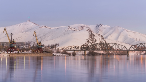 Beautiful Colorful Dusk on a River in Winter. Silhouettes of Barge, Reeds, Cranes and Railway