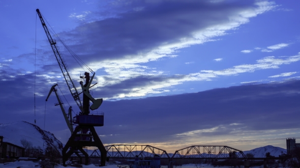 of Beautiful Colorful Dusk on a River in Winter. Silhouettes of Barge, Reeds, Cranes and Railway