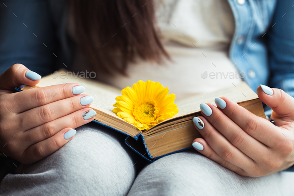Girl\'s hands on a book with a yellow flower