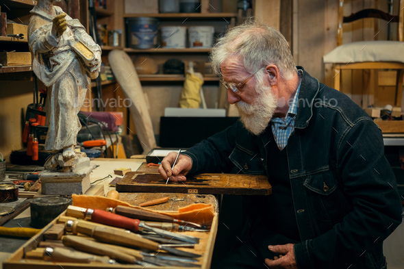 Senior wood carving professional during work
