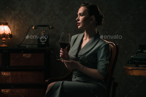 Beautiful woman with glass of wine in retro interior