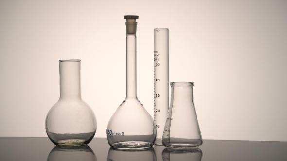 Chemical Glass Flasks and Test Tube Reflecting on the Surface Spinning Against