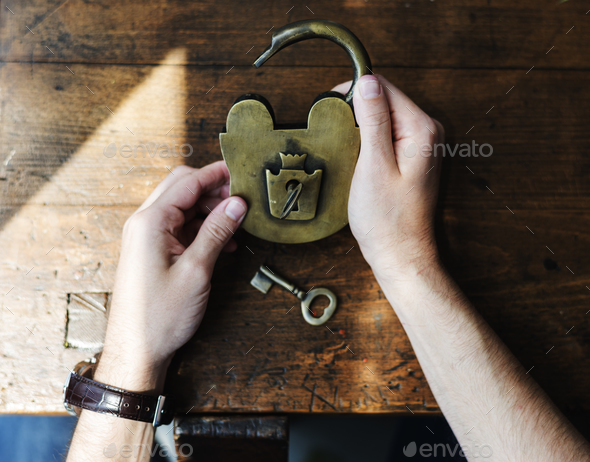 Hands Holding Unlock Padlock and Key on Wooden Table
