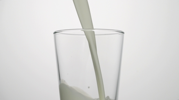 Shot of Milk Pouring Into Empty Glass