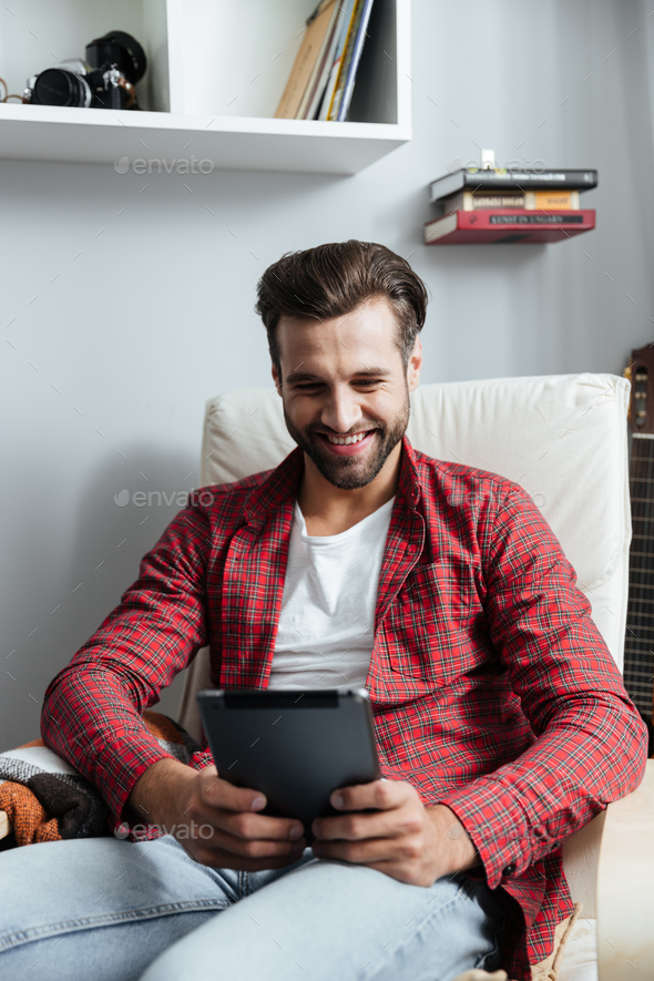 Smiling young bearded man using tablet computer. - Stock Photo - Images