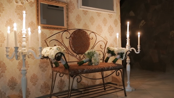 Bouquets on a Bench on the Background of Wedding Decorations. On the Sides of the Candles in