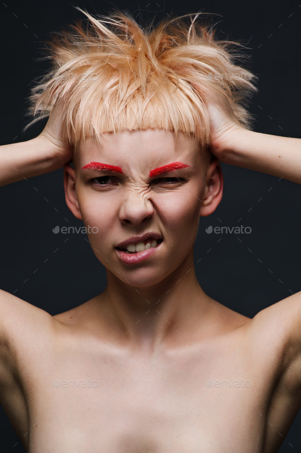 Close up on face of crazy mad cocky young woman with stylish dyed pink hair, hands ruffle her