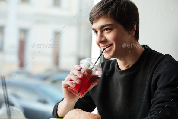 Happy young man sitting in cafe drinking juice. - Stock Photo - Images