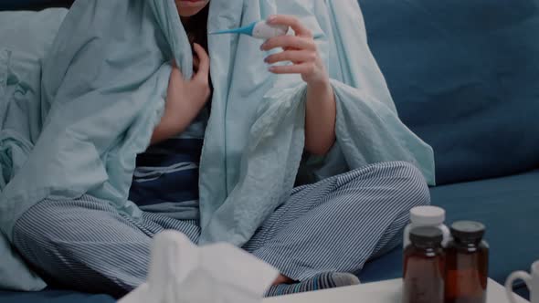 Woman with Fever Using Thermometer to Check for Virus Symptoms alt