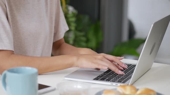 Asian woman working at home and typing keyboard using a laptop.