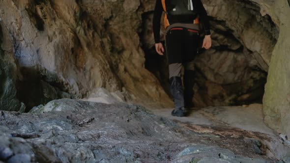 Men's feet in black sportswear  go to the cave with climbing equipment alt