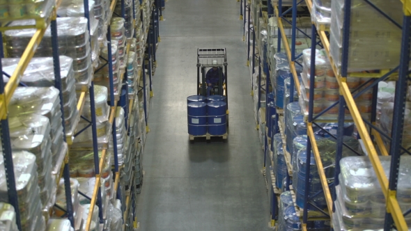 Man on Forklift Transporting Barrels in Warehouse alt