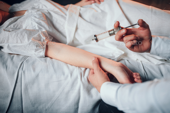 Male doctor makes syringe injection to sick woman - Stock Photo - Images