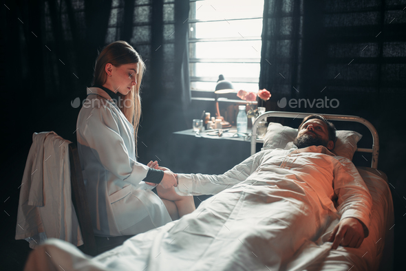 Female doctor measures the pulse of sick man - Stock Photo - Images