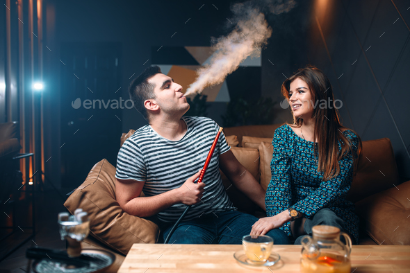 Young couple smoking hookah on leather couch Stock Photo by NomadSoul1